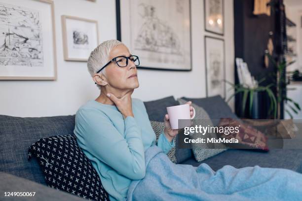 hogere vrouw die thee thuis wegens de zere keel drinkt - warme dranken stockfoto's en -beelden