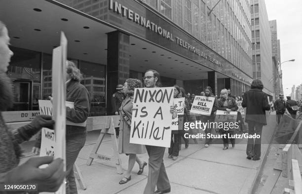Demonstrators walk in front of the International Telephone and Telegraph Building, holding anti-Nixon and anti-ITT signs, participating in Vietnam...
