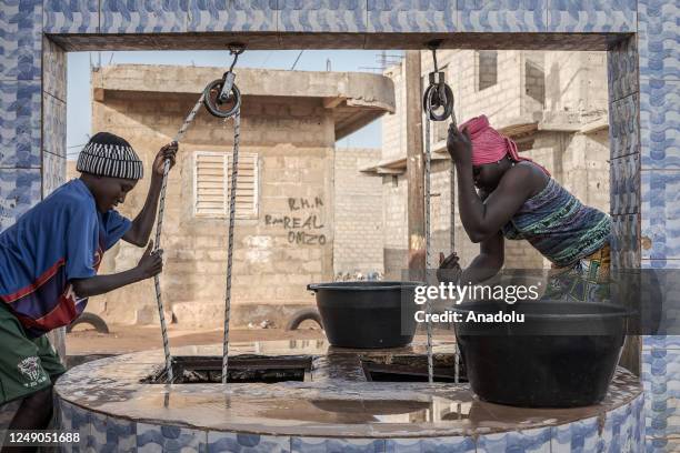 People fill buckets with clean water from a water well ahead of the World Water Day in Dakar, Senegal on March 18, 2023. World Water Day is held...