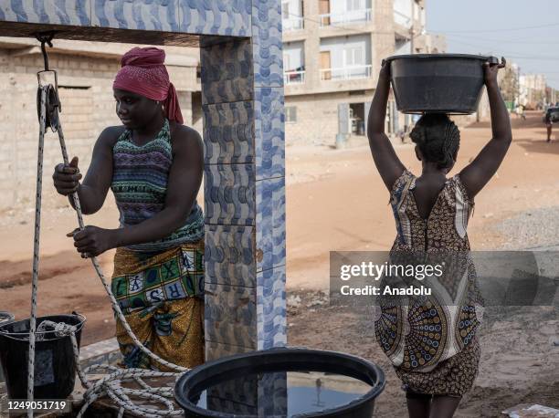 People fill buckets with clean water from a water well ahead of the World Water Day in Dakar, Senegal on March 18, 2023. World Water Day is held...