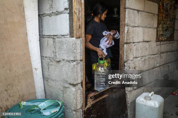 Year-old Mary Anne Santana, a mother of 15 children, âcarries a refilled water jug inside their house âat Baseco Compound in Tondo, Manila,...