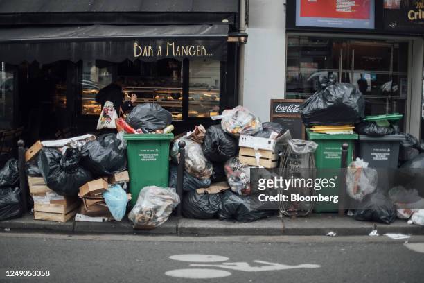 Uncollected garbage bins and bags of trash outside a restaurant during a sanitation workers strike in Paris, France, on Tuesday, March 21, 2023. Due...