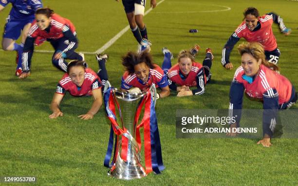 Olympique Lyonnais' players dive across the grass beside the trophy after beating FFC Turbine Potsdam during the UEFA Women's Champions League Final...