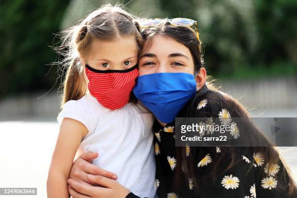 two cheerful girls wearing face protective mask - sibling stock pictures, royalty-free photos & images