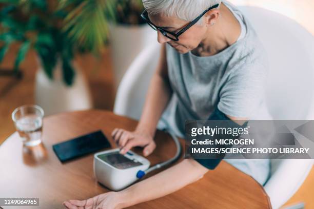 senior woman measuring blood pressure - blood pressure gauge stock pictures, royalty-free photos & images