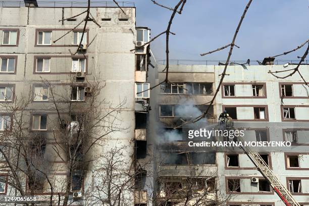 Firefighters work on a fire at a damaged building after an air strike in the city of Zaporizhzhia on March 22 amid the Russian invasion of Ukraine. -...