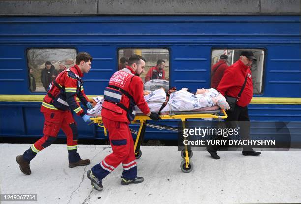 Medical workers transfer a wounded civilian patient from a train to an ambulance upon his arrival from the east of Ukraine in the western Ukrainian...