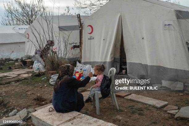 Displaced woman feeds her daughter in front of their tent in a refugee camp in Adiyaman on March 22, 2023. - On February 6 a 7.8-magnitude earthquake...