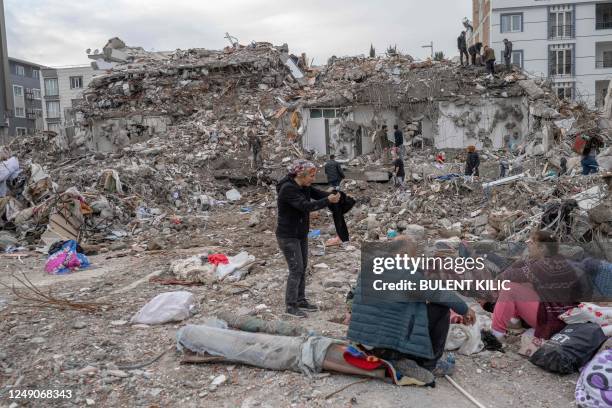 Family sit in front of their former house, destroyed after the 7.8-magnitude earthquake, in Adiyaman, on March 22, 2023. - On February 6 a...