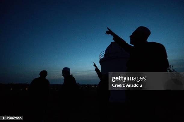 Islamic religious officials gesture after observing the position of the moon through a telescope during the sighting of the new moon for the Muslim...