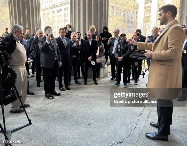 March 2023, USA, New York: Auctioneer Matthew D. Mannion , in haber of the auction house Mannion Auctions, speaks to bidders during the auction of...