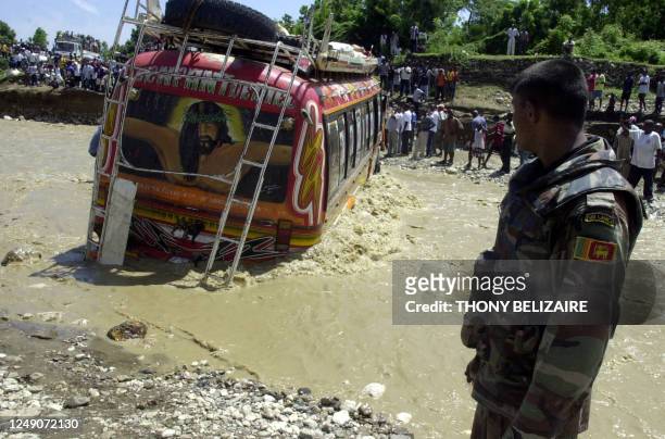 Soldier watches a bus as it attempts to cross a flood-swollen river 29 August 2006 after the collapse of a bridge in Grand Goave, 54 km south of...
