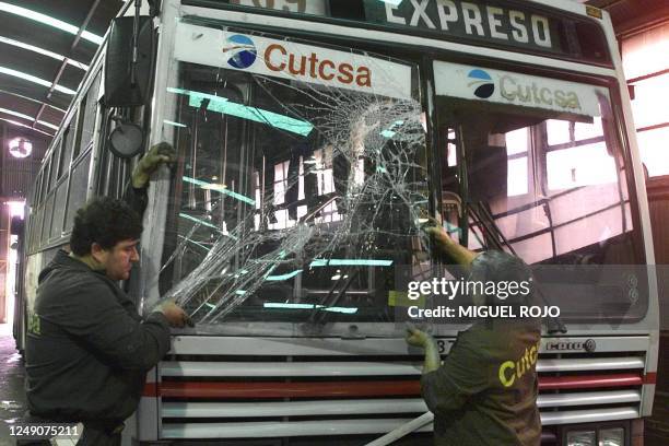 Workers change the windshield of a coach in Montevideo, Uruguay 08 June during the strike summoned by central union PIT-CNT against the government's...