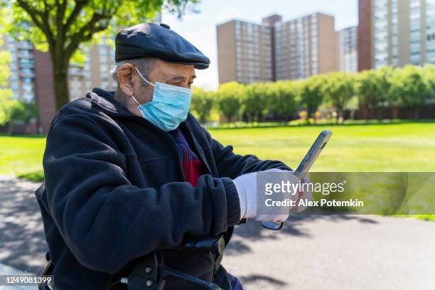 portrait of the senior 90-years-old man wearing a protective mask and gloves because of the covid-19 pandemic, using a smartphone for video call with his family. - alex potemkin coronavirus stock pictures, royalty-free photos & images