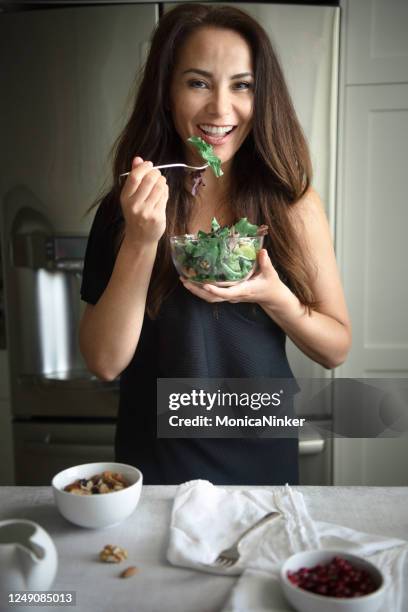 healthy mature woman eating organic salad at home - mature women eating stock pictures, royalty-free photos & images