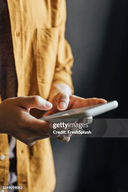 happy asian man in a yellow shirt using a smartphone to check social media - close up hand smart phone stock pictures, royalty-free photos & images