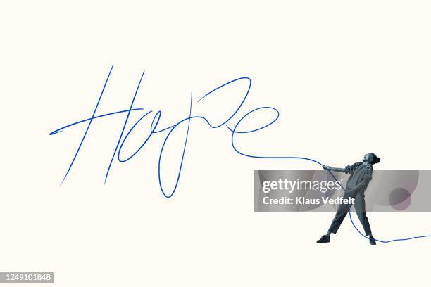 young woman pulling blue rope forming word hope - grande tablée photos et images de collection