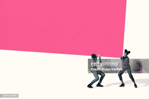 young man and woman carrying large pink block - togetherness stock pictures, royalty-free photos & images