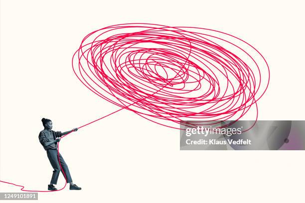 woman pulling vibrant red rope from tangle - controlling stock-fotos und bilder