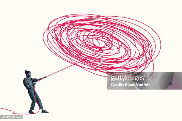 woman pulling vibrant red rope from tangle - problemen stockfoto's en -beelden