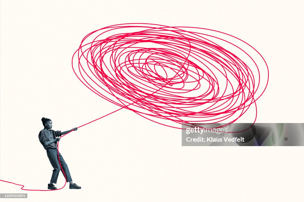 Woman pulling vibrant red rope from tangle