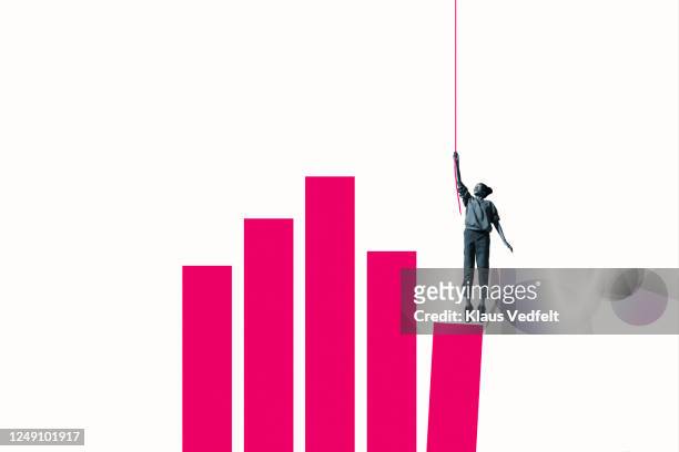 woman hanging from rope over pink bar graph - bias stock-fotos und bilder