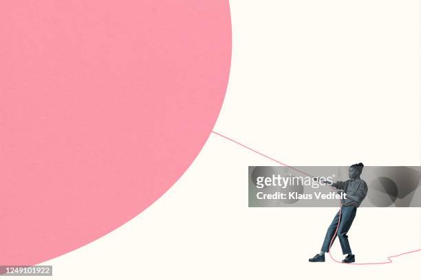 woman pulling large pink helium balloon with rope - determinazione foto e immagini stock