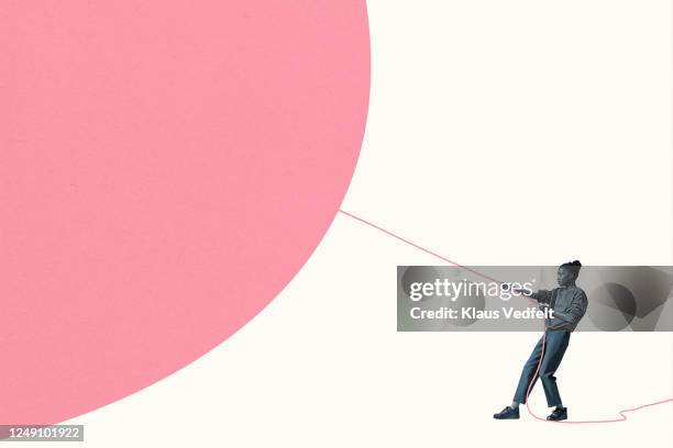 woman pulling large pink helium balloon with rope - pulling stockfoto's en -beelden