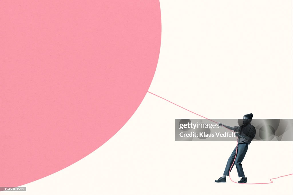 Woman pulling large pink helium balloon with rope