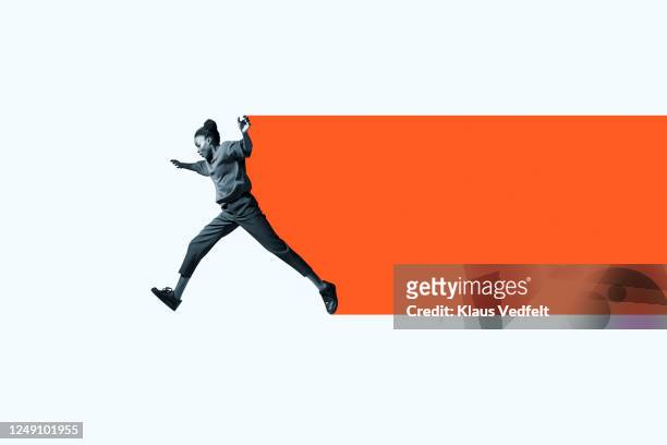 full length of woman jumping with orange trail - vitalità foto e immagini stock
