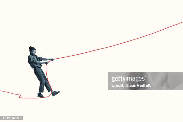 side view of young woman pulling vibrant red rope - pull foto e immagini stock