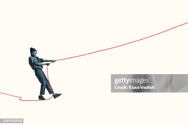 side view of young woman pulling vibrant red rope - arrastar imagens e fotografias de stock