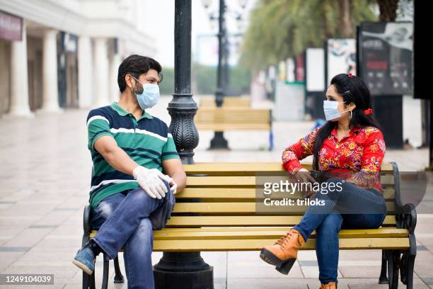 couple sitting outdoors with social distancing - social distancing stock pictures, royalty-free photos & images
