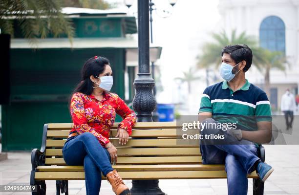 couple sitting outdoors with social distancing - india covid stock pictures, royalty-free photos & images