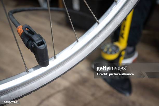 March 2023, Hesse, Frankfurt/Main: A mechanic pumps up a bicycle tire during an inspection at the Schraube & Rad bicycle workshop. Photo: Sebastian...