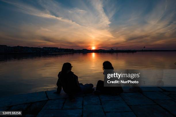 Two girls sitting in front of the sea at sunset on the Port of Molfetta in Puglia, on March 22, 2023. World Water Day is celebrated on March 22,...