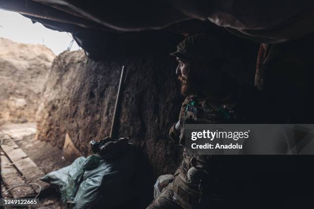 Ukrainian soldiers take shelter from Russian shelling in a trench in the direction of Bakhmut, 22 March 2023.