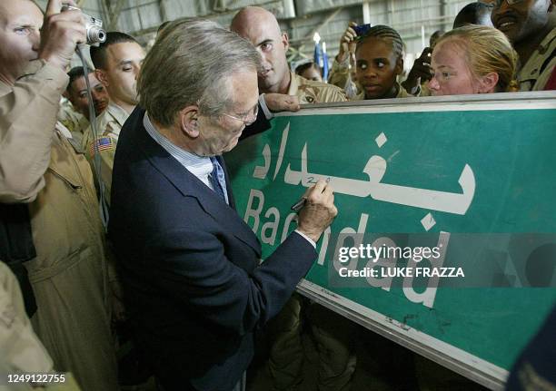 Secretary of Defense Donald Rumsfeld signs a Baghdad road sign at the request of a US soldier 30 April 2003 during his visit with US troops at...