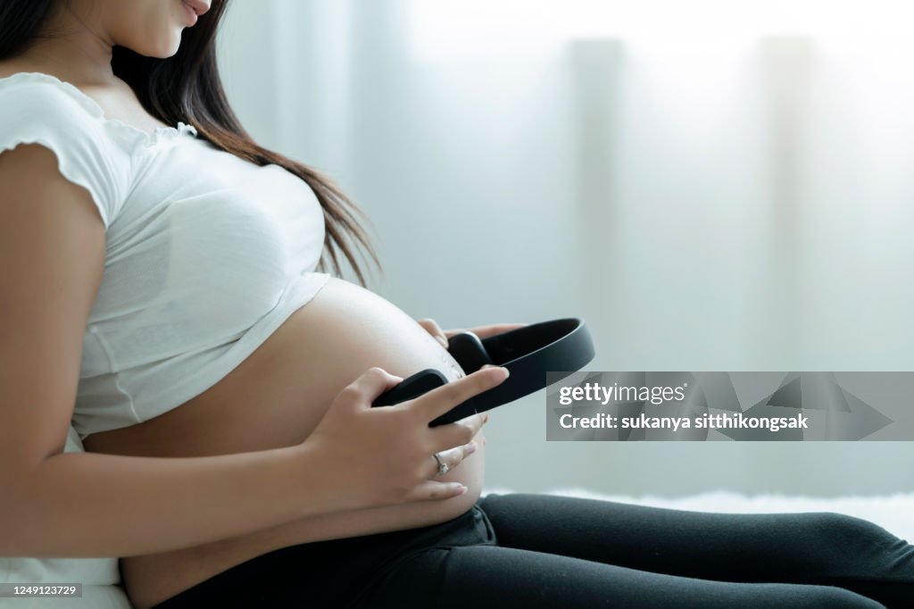 Pregnant Hispanic Woman Holding Headphones On Belly High-Res Stock Photo -  Getty Images