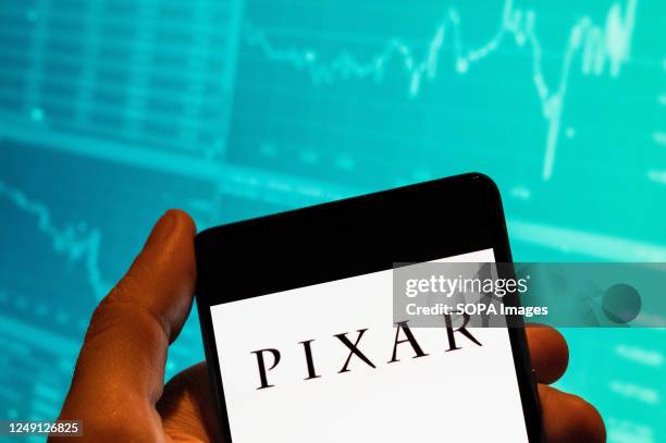 In this photo illustration, the American computer animation film studio owned by Disney, Pixar logo seen displayed on a smartphone with an economic...