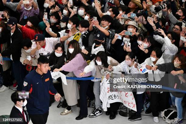 Hundreds of fans crowd together and cheer as members of Japans national baseball team arrive from the US, including Japan's Kazuma Okamoto , at...