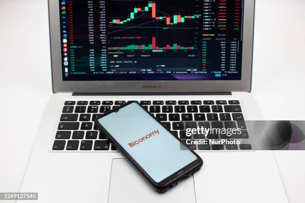 In this photo illustration a Biconomy logo seen displayed on a smartphone screen and an Exchange graph on a MacBook screen in Athens, Greece on March...