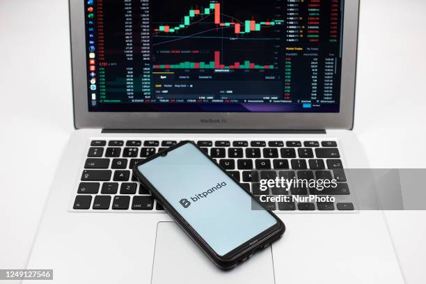 In this photo illustration a Bitpanda logo seen displayed on a smartphone screen and an Exchange graph on a MacBook screen in Athens, Greece on March...