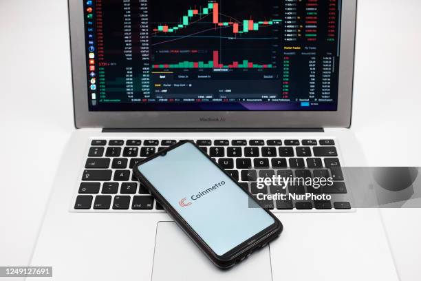 In this photo illustration a Coinmetro logo seen displayed on a smartphone screen and an Exchange graph on a MacBook screen in Athens, Greece on...