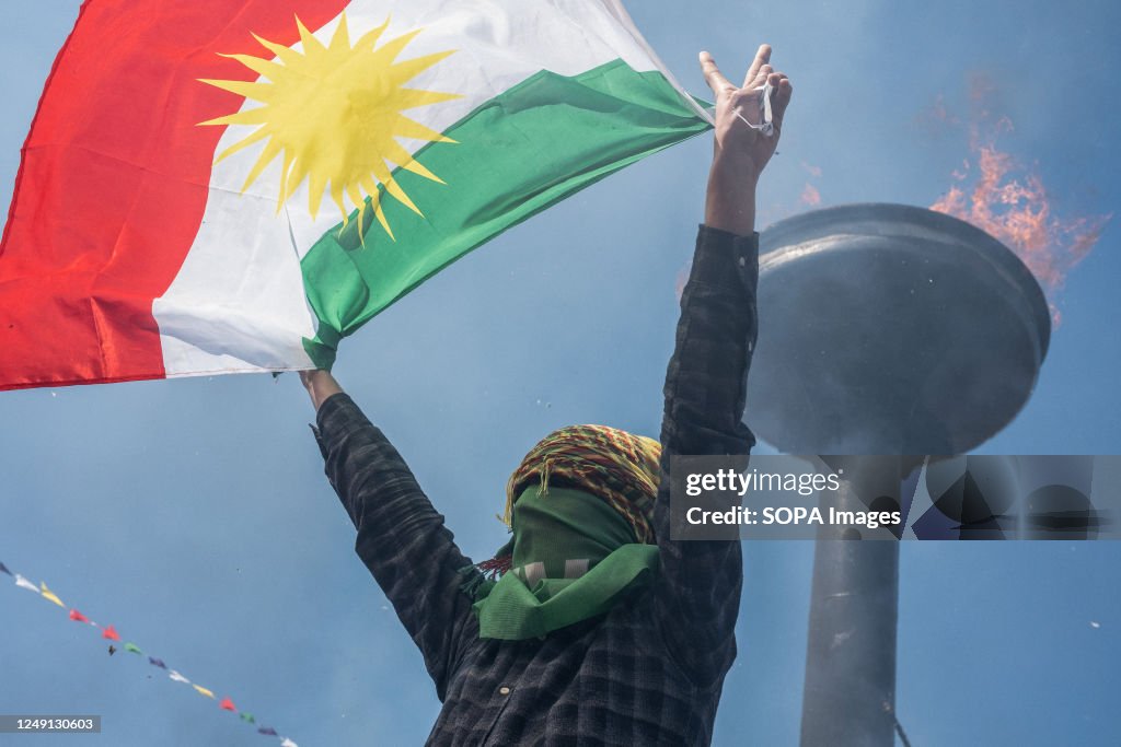 A young man with his face covered holding the Iraqi Federal