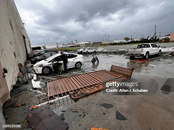 Montebello, CA An employee who was inside the Royal Paper Box Company when the roof was torn off from a confirmed tornado views his damaged car at...