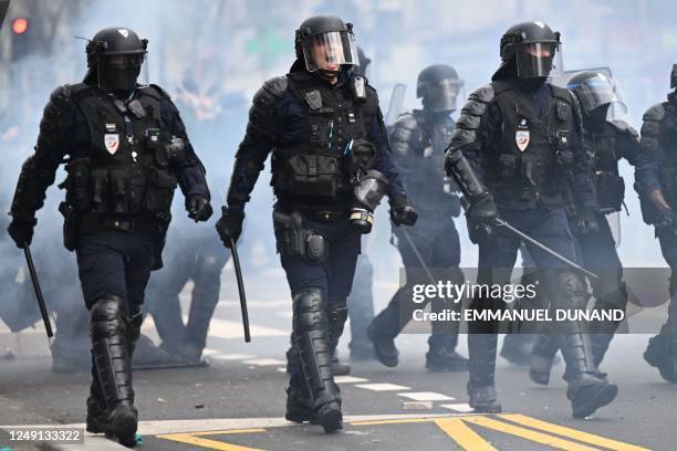 Riot police officers walk towards demonstrators during a rally a week after the government pushed a pensions reform through parliament without a...