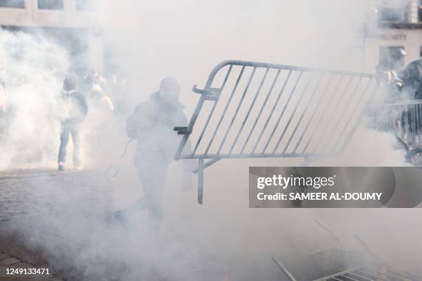 Protester throws a fence towards anti-riot police officers during a demonstration on a national action day, a week after the government pushed a...