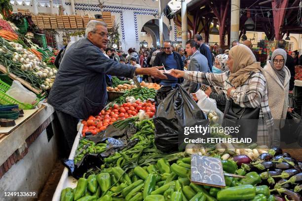 Produce merchant exchanges banknotes with a customer at the Central Market in Tunis on March 23 as people shop on the first day of the Muslim holy...