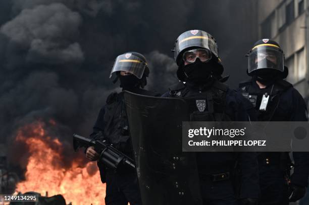 Anti-riot police officers stand guard next to a fire set by protesters during a demonstration on a national action day, a week after the government...